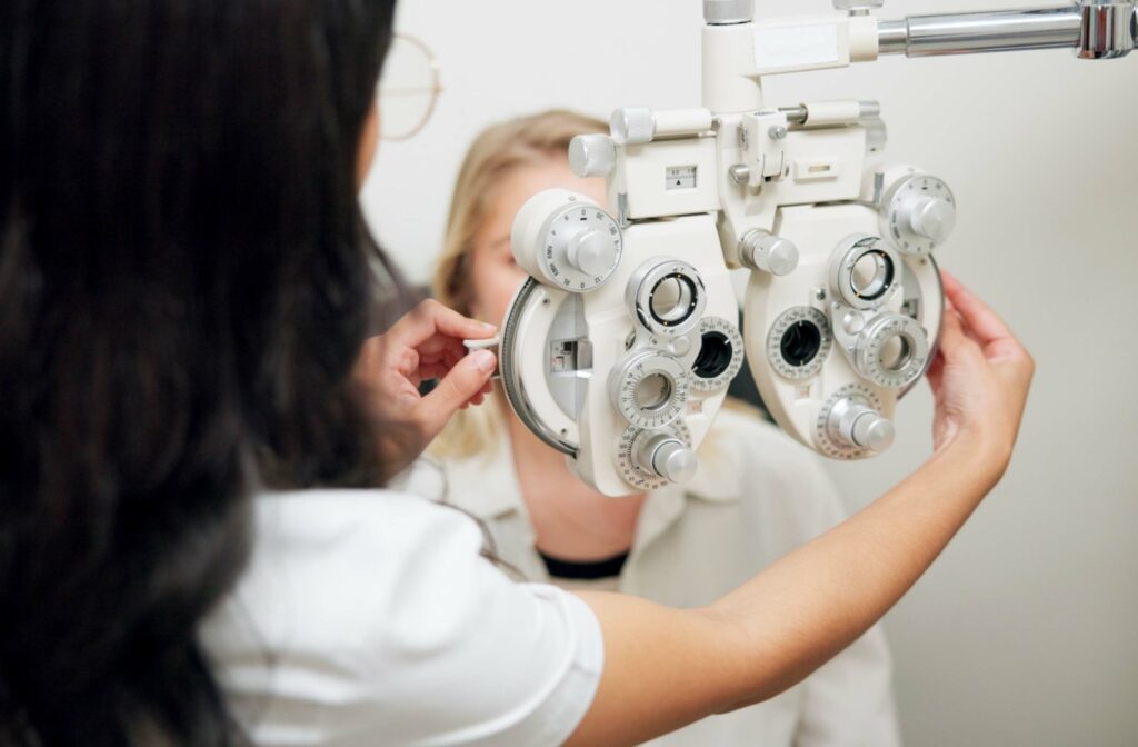 An optometrist prepares a phoropter for a patient during a refraction test.