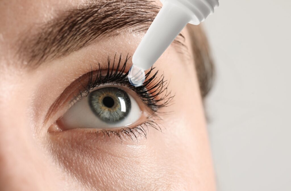 A close up of a woman's eye as she applies medicated eye drops.