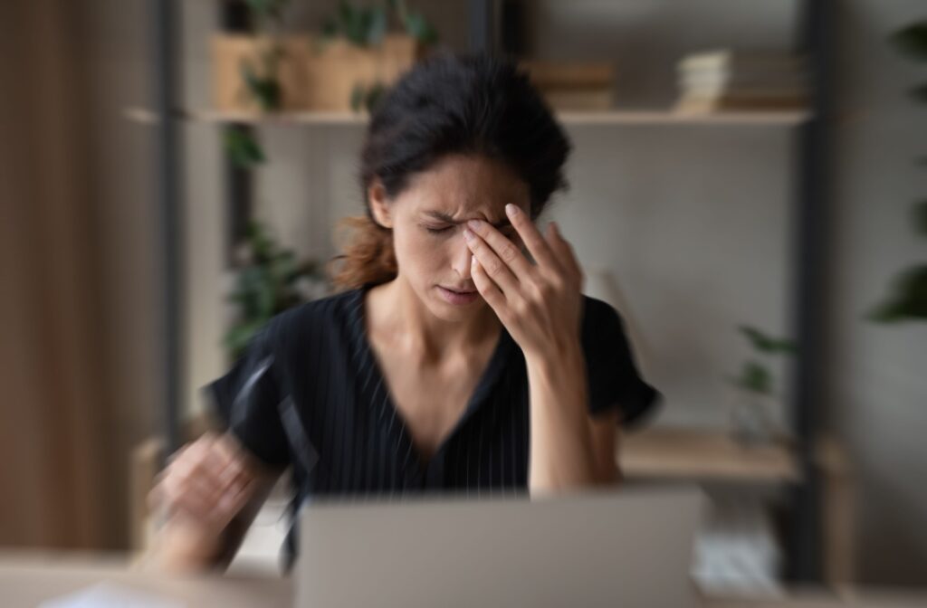 A woman experiencing dry eye pain and blurry vision, clutching her face.