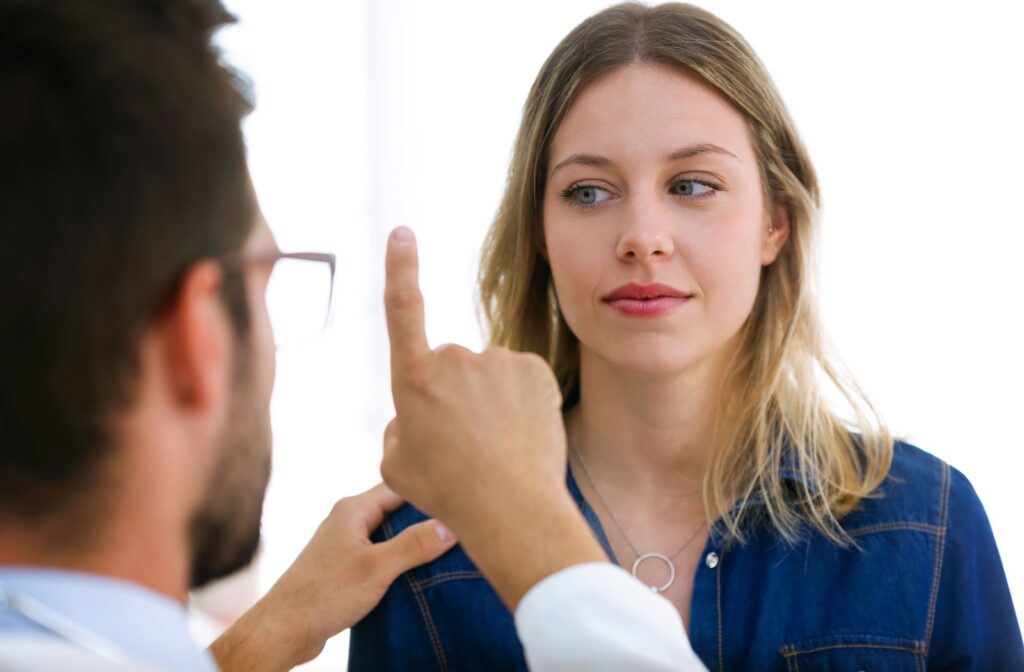 A woman in an eye exam follows the eye doctor's finger with her eyes.