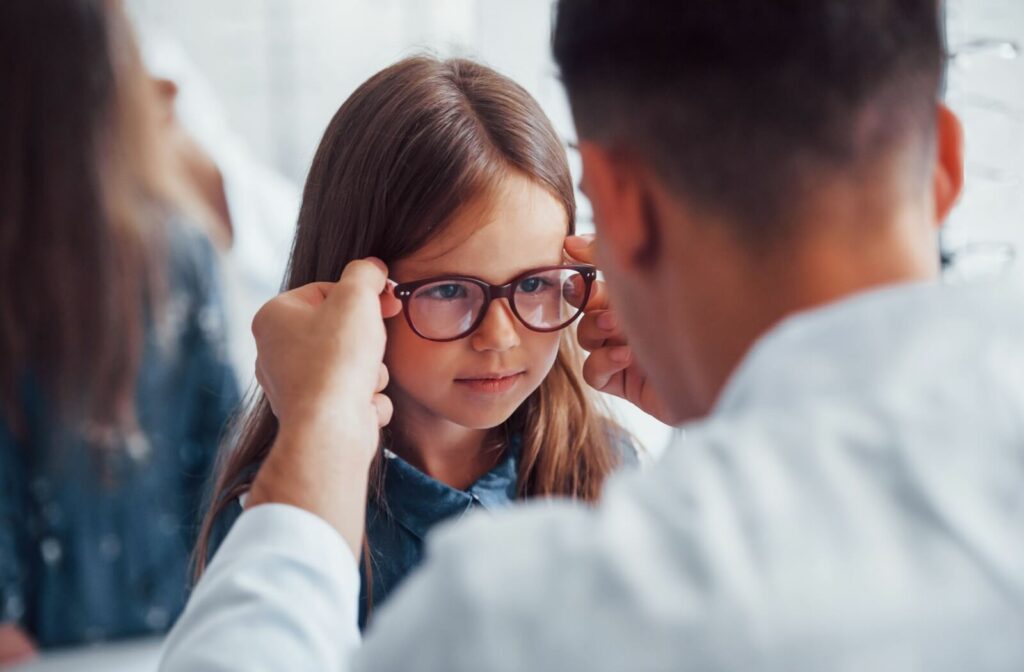 A blurry adult with blonde hair lifts their eyeglasses, pointing an in-focus finger straight ahead