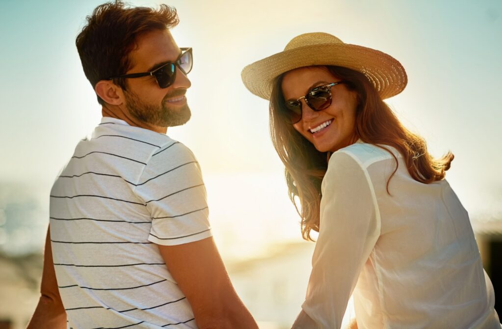 A young couple wearing sunglasses together at the beach.