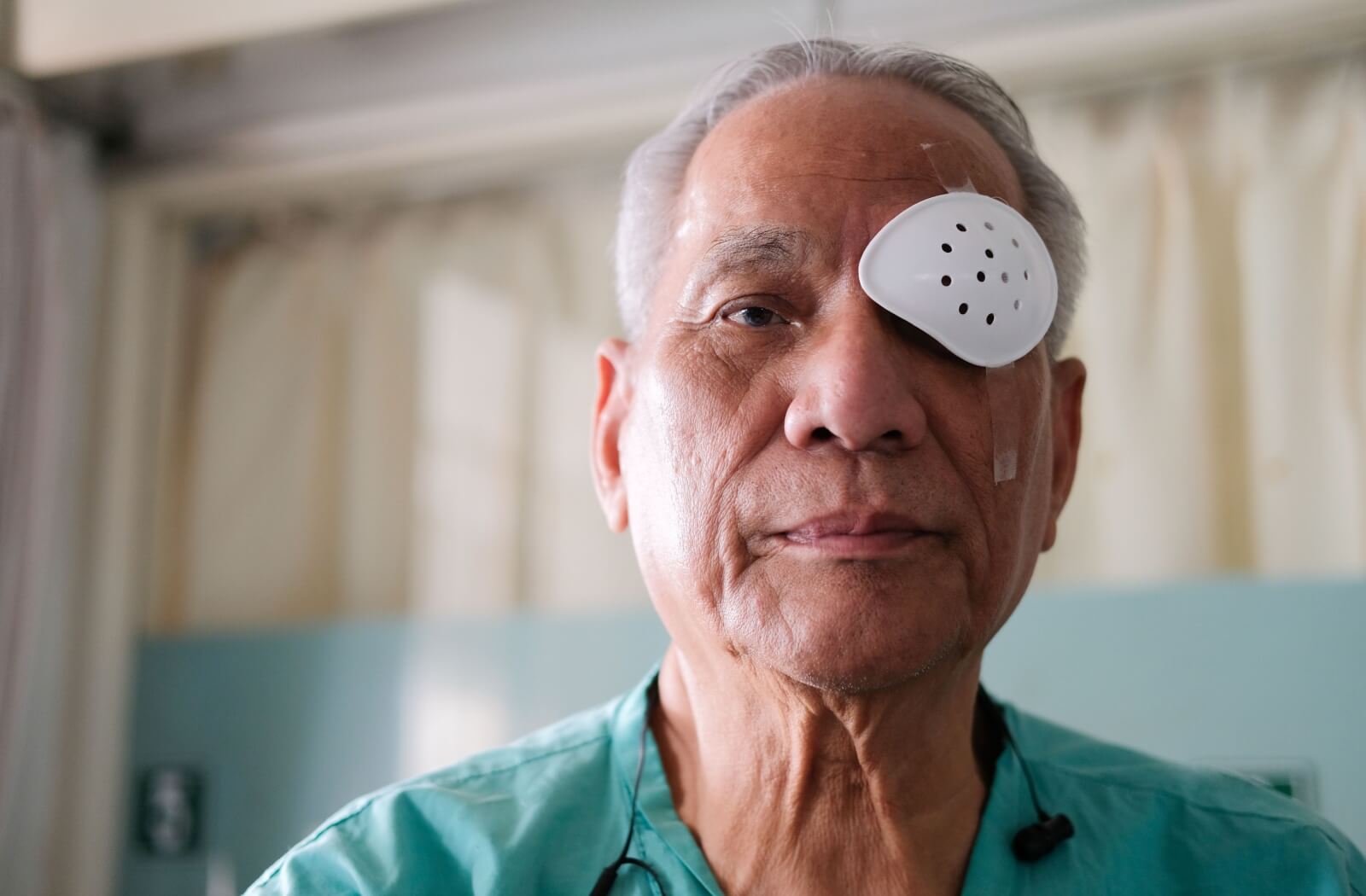 Older man wearing a white perforated shield over left eye.