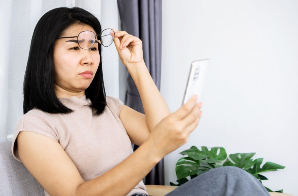 Person squinting at their phone because they have the wrong glasses prescription