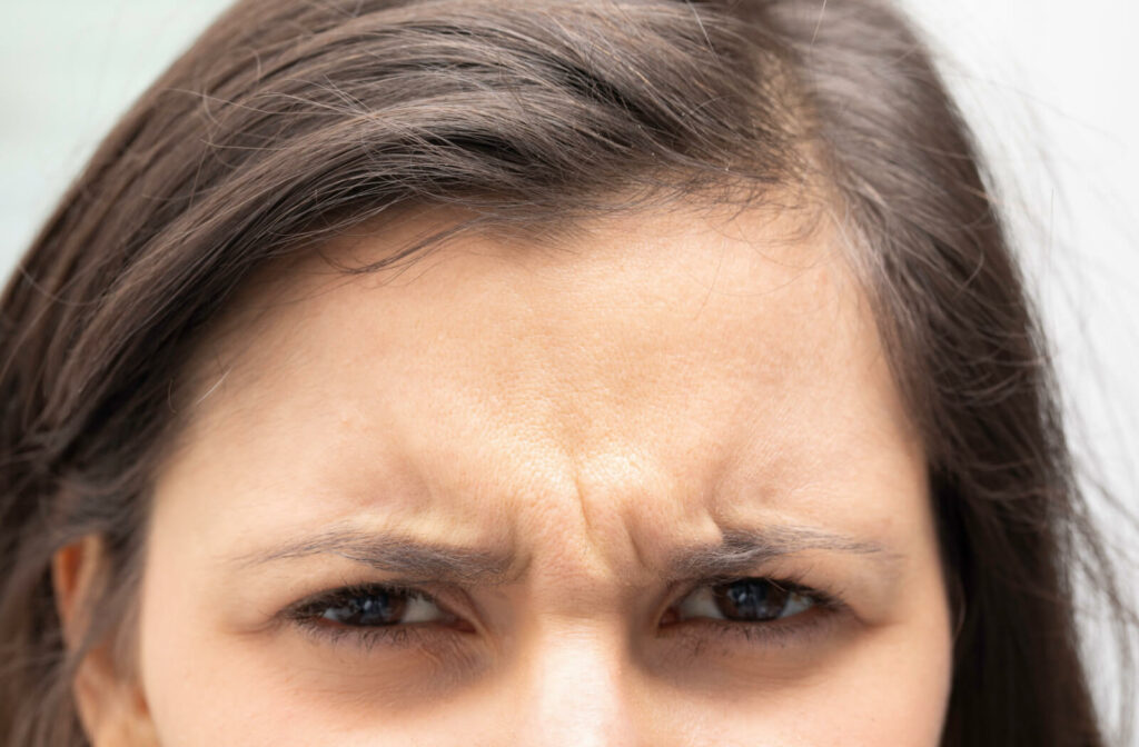 A close-up view of a young woman frowning forehead.