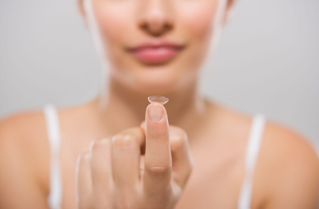 A lady holding up a contact lens on her finger
